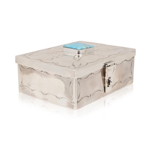 May include: A silver box with an intricate design and a turquoise stone inlay on the lid. The box has a hinged lid and a latch.