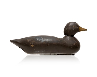 May include: A wooden duck decoy with a dark brown finish. The decoy has a realistic shape and features a painted eye.