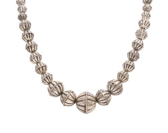 May include: A silver necklace with round, textured beads. The necklace has a larger, round bead in the center.