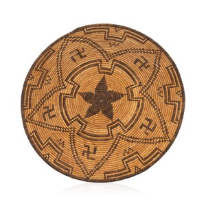 May include: A round woven basket with a brown and tan star design. The basket is made of natural materials and has a traditional Native American style.