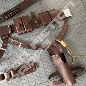 May include: A brown leather belt with multiple pouches and a holster. The belt has a buckle and is decorated with stitching. The holster is for a pistol and has a strap.