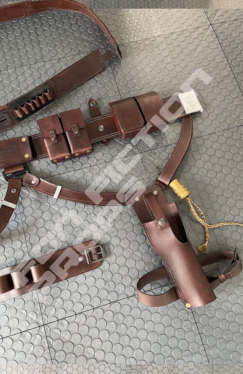 May include: A brown leather belt with multiple pouches and a holster. The belt has a buckle and is decorated with stitching. The holster is for a pistol and has a strap.