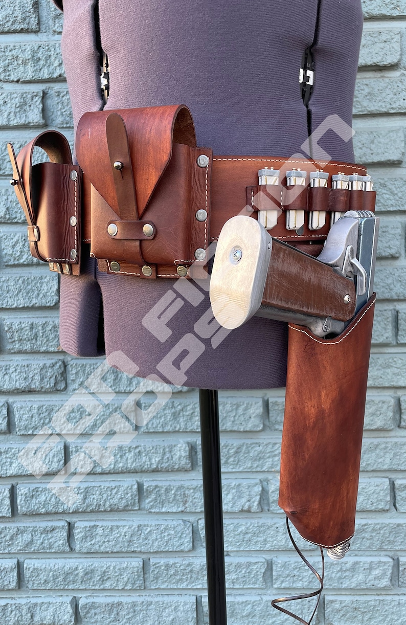 May include: A brown leather belt with multiple pouches and a holster for a silver pistol. The belt is worn on a mannequin with a grey shirt.