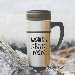 May include: A stainless steel travel mug with a black handle. The mug has the text "WORLD'S BEST MOM" printed on it.