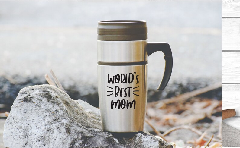 May include: A stainless steel travel mug with a black handle. The mug has the text "WORLD'S BEST MOM" printed on it.