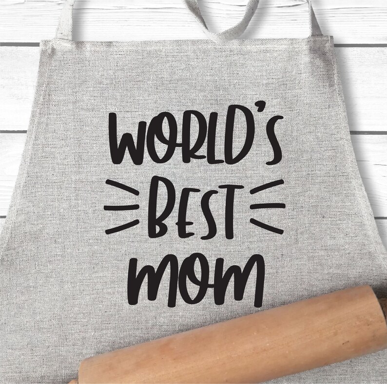 May include: A gray linen apron with black text that reads "WORLD'S BEST MOM". A wooden rolling pin is in the foreground.