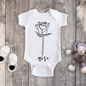 May include: White baby onesie with a black line drawing of a rose and the word "rose" printed below the rose.