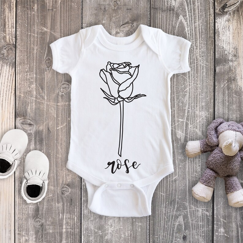 May include: White baby onesie with a black line drawing of a rose and the word "rose" printed below the rose.