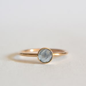 May include: A delicate gold ring with a light blue gemstone. The ring is simple and elegant, perfect for everyday wear.