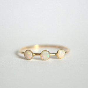 May include: A gold ring with three white opal stones set in a row.