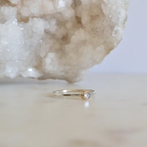 May include: A silver ring with a hammered texture and a small, clear gemstone set in a gold bezel.