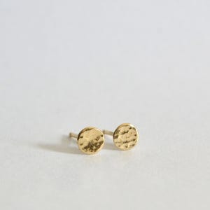 May include: A pair of gold hammered circle stud earrings.