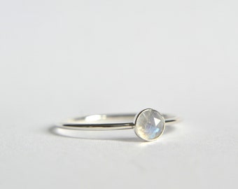 May include: A silver ring with a round, iridescent moonstone.