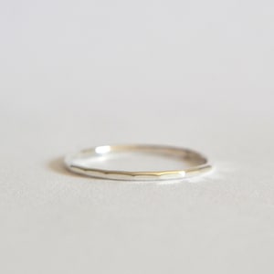 May include: A thin silver band ring with a hammered texture.
