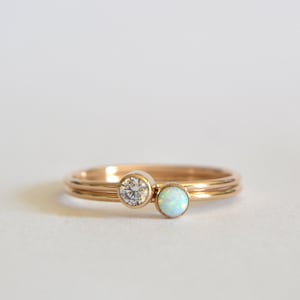 May include: Two gold rings with a single round diamond and a round opal gemstone.