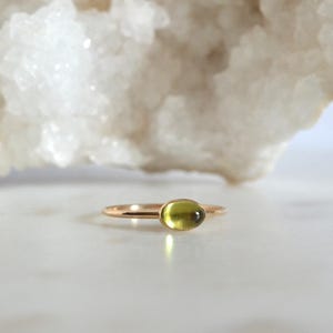 Puede incluir: Un anillo de oro con una piedra ovalada verde claro.
