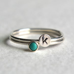 May include: A silver ring with a turquoise stone and a silver band with the letter "K" engraved on it.