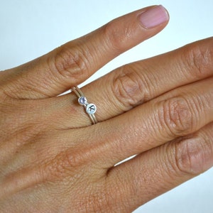 May include: A silver ring with a small purple gemstone and a letter 'K' charm.