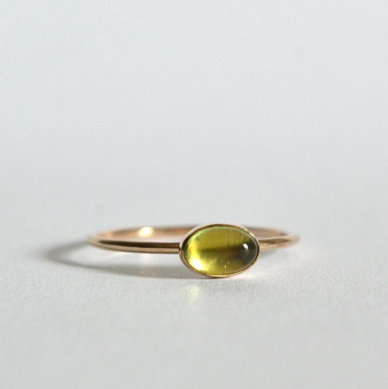 Puede incluir: Un anillo de oro con una piedra ovalada verde.