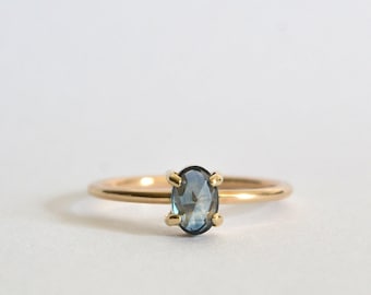 May include: A gold ring with a blue oval gemstone set in a prong setting.