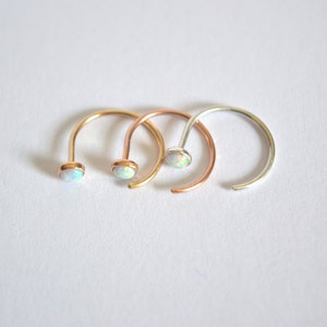 Pode incluir: Tr&ecirc;s argolas de nariz com pedras de opala. As argolas s&atilde;o de prata, ouro e ouro rosa.