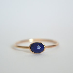 May include: A gold ring with a dark blue oval-shaped gemstone.