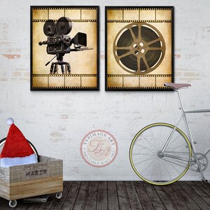 May include: Two vintage-style movie posters with a film reel and a movie camera. The posters are framed in black and have a white brick wall background. A silver bicycle with a brown leather seat is in the foreground.