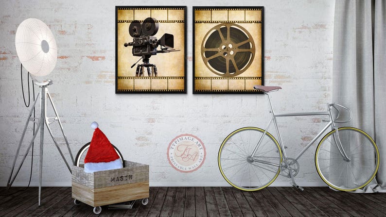 May include: Two vintage-style movie posters with a film reel and a movie camera. The posters are framed in black and have a white brick wall background. A silver bicycle with a brown leather seat is in the foreground.