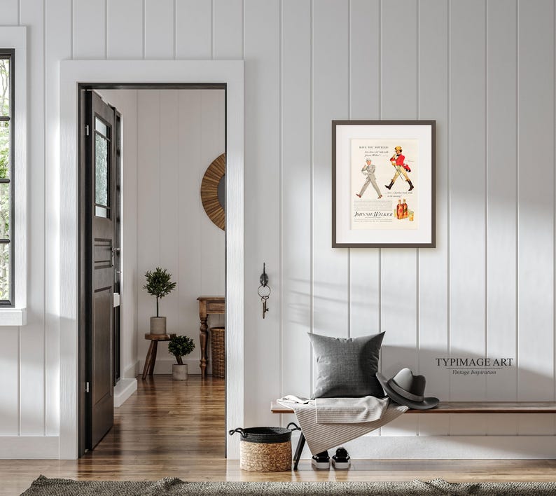 May include: A framed vintage advertisement for Johnnie Walker scotch whisky. The ad features a man in a red coat walking with a walking stick. The text reads "See the difference in the Scotch you buy" and "Johnnie Walker".