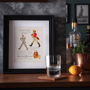 May include: A framed vintage advertisement for Johnnie Walker scotch whisky. The ad features two men walking in opposite directions, one in a red coat and the other in a white suit. The text reads "Have you noticed...those who walk...with Johnnie Walker...have a familiar head ache in the morning?"