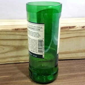 May include: A green glass bottle with a label that reads "Discover our taste and story at JohnJamesonWhiskey.com. Bottled by John Jameson & Son, Inc. New York, NY.  From the Midleton Distillery, Co. Cork, Ireland."