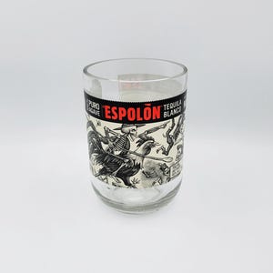 May include: Clear glass with a label featuring the text "Espolon Tequila Blanco" and a black and white illustration of skeletons riding chickens. The glass has a shamrock logo that says "Irish Glass".