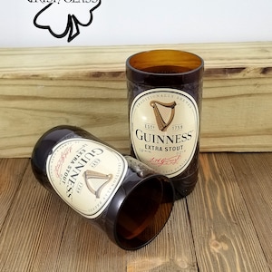 May include: Two brown glass Guinness beer bottles repurposed into drinking glasses. The bottles have the Guinness logo and text, "Traditionally Brewed", "Est. 1759", "Extra Stout", and "Arthur Guinness, Dublin".