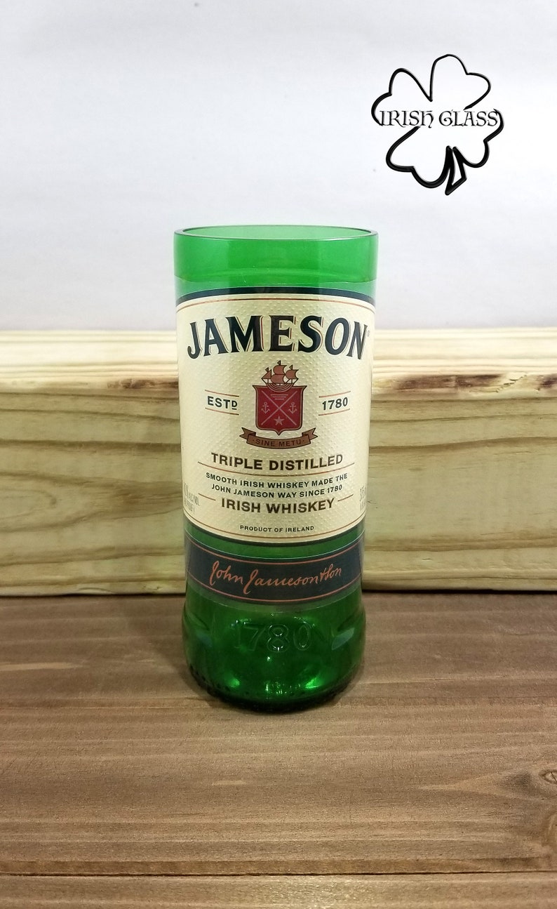 May include: A green glass with a Jameson Irish Whiskey label. The label features the Jameson logo, the words "Triple Distilled", "Smooth Irish Whiskey Made the John Jameson Way Since 1780", "Irish Whiskey", and "Product of Ireland".