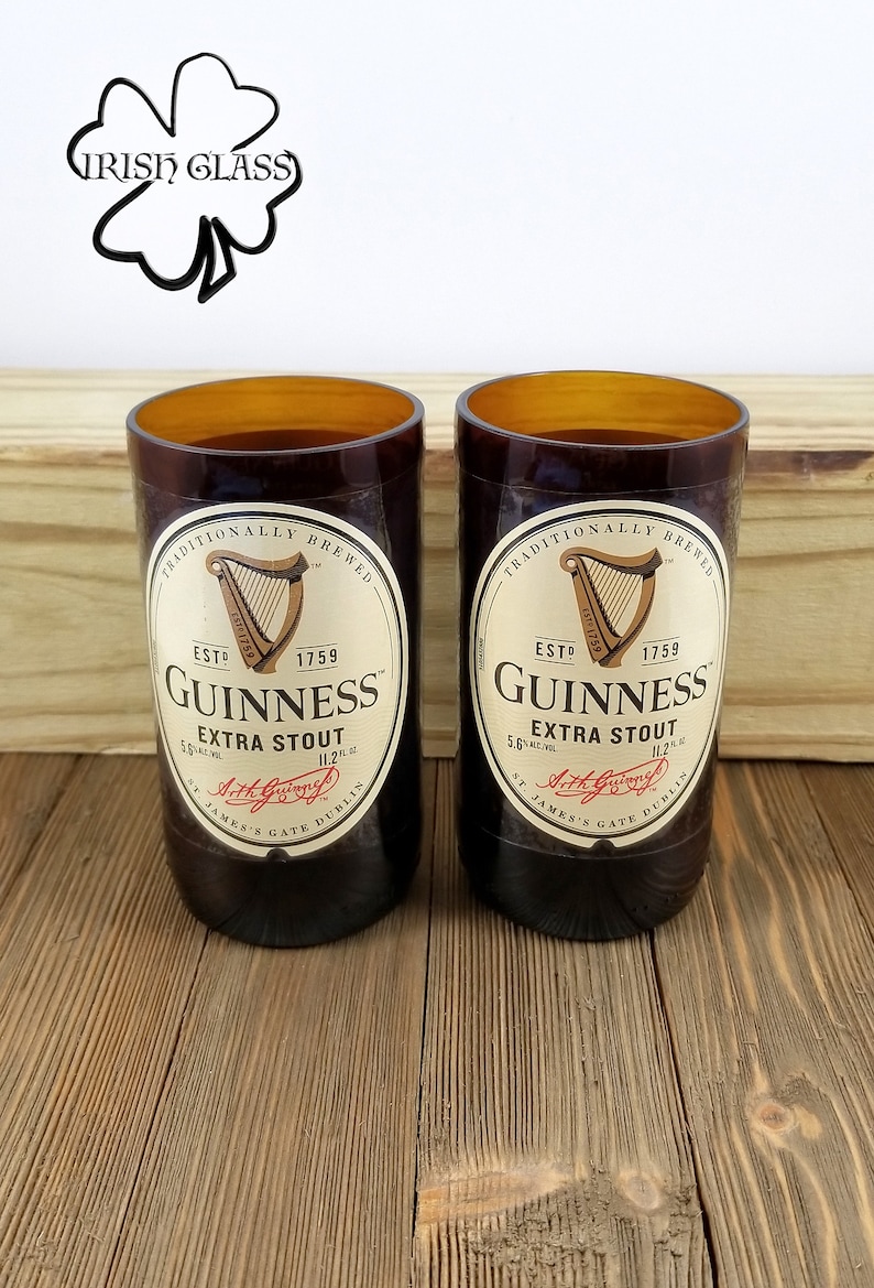 May include: Two brown glass Guinness beer bottles with the Guinness logo and text "Traditionally Brewed", "Est. 1759", "Guinness", "Extra Stout", "5.6% Alc./Vol.", "11.2 fl. oz.", "St. James's Gate Dublin", and "Arthur Guinness" printed on the label.