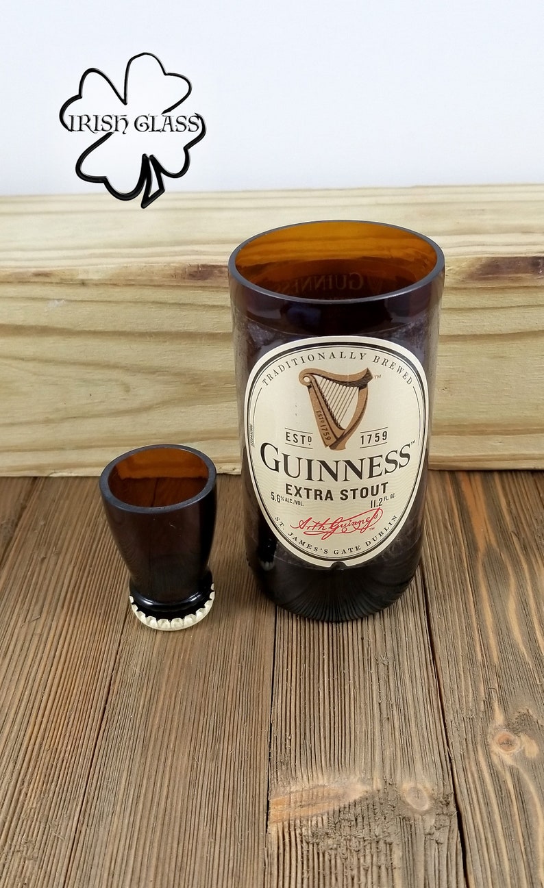 May include: Two brown glass shot glasses, one larger than the other. The larger glass is a repurposed Guinness beer bottle with the label visible. The label reads "Traditionally Brewed", "Est 1759", "Guinness", "Extra Stout", "St. James's Gate Dublin".