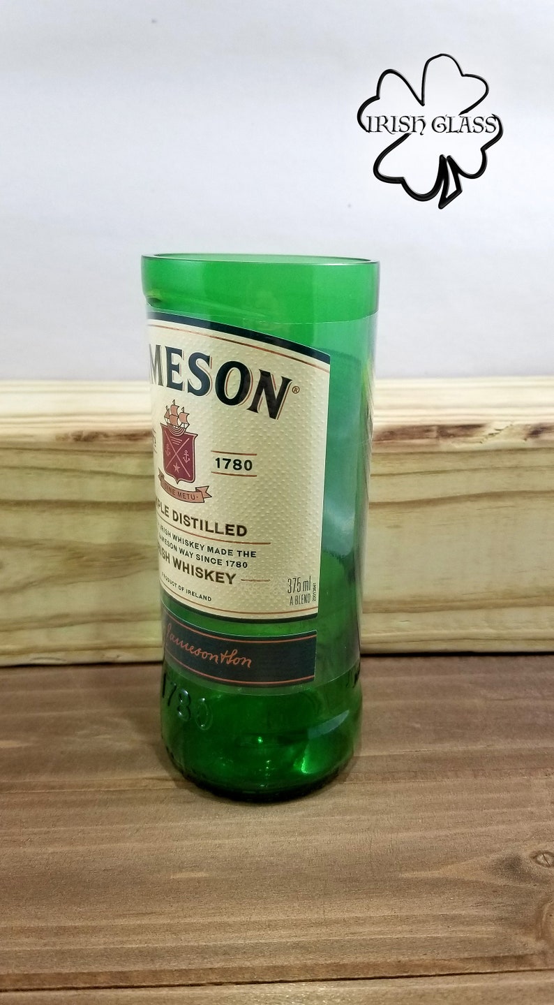 May include: A green glass shot glass with a Jameson Irish Whiskey label. The label features the Jameson logo, the year 1780, and the text "Triple Distilled Irish Whiskey Made the Jameson Way Since 1780".