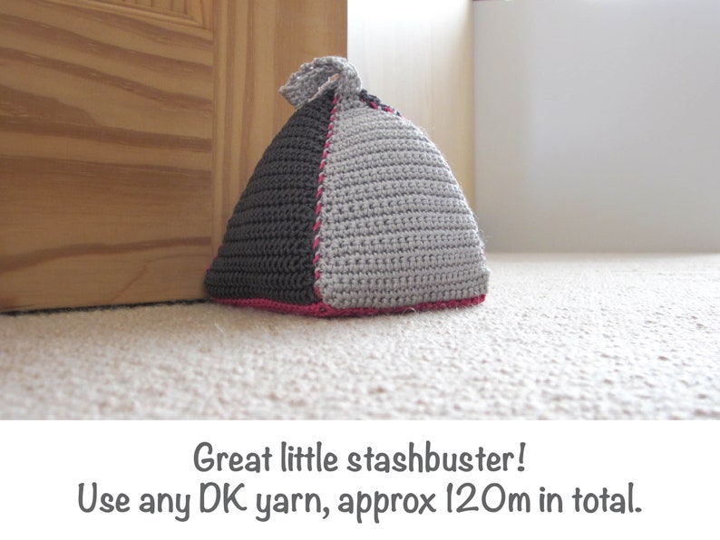 May include: A gray and black crocheted doorstop in the shape of a triangle with a pink trim.  Great little stashbuster! Use any DK yarn, approx 120m in total.