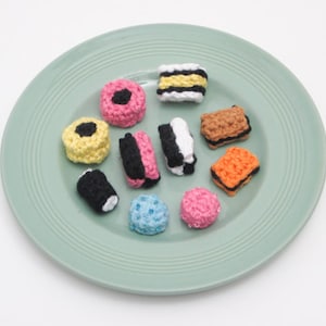 May include: A plate of crocheted candy, including black and white licorice, yellow and black licorice, pink and black licorice, orange and black licorice, and a few other assorted colors.