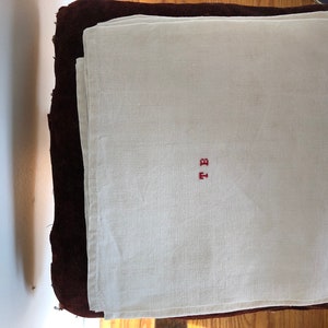 May include: A white linen napkin with red embroidered initials "T.B."