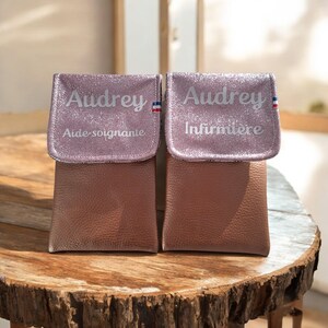 May include: Two small, brown pouches with glittery pink flaps. Each flap is personalized with the name "Audrey" and a French flag design. One pouch reads "Aide-soignante" and the other reads "Infirmi&egrave;re".