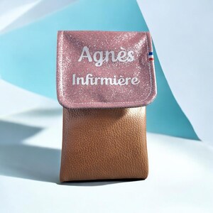 May include: A two-tone case with a pink glittery flap and a brown body. The flap has the name "Agnes" and the word "Infirmi&egrave;re" printed in white. A small French flag is on the right side of the flap.