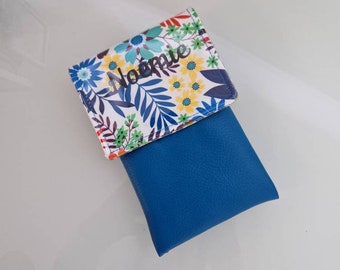 May include: A blue and white floral patterned pouch with the name "Noemie" printed on it. The pouch is made of fabric and has a blue leather flap.