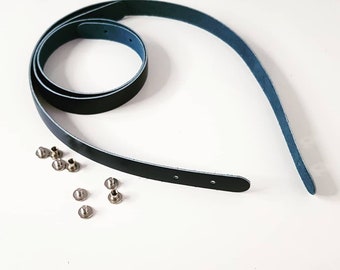 May include: A dark blue leather strap with silver metal rivets. The strap is coiled and ready to be used for a craft project.