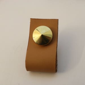 May include: A brown leather cabinet pull with a gold metal knob.