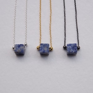 Peut inclure: Trois colliers avec des pendentifs en pierre bleue et blanche. Les colliers sont en argent, en or et en noir.