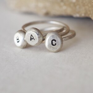 May include: Three silver rings with the letters A, B, and C engraved on them.