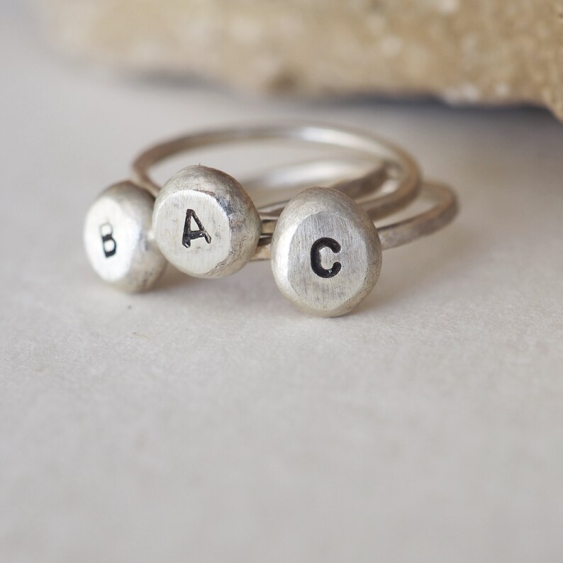 May include: Three silver rings with the letters A, B, and C engraved on them.
