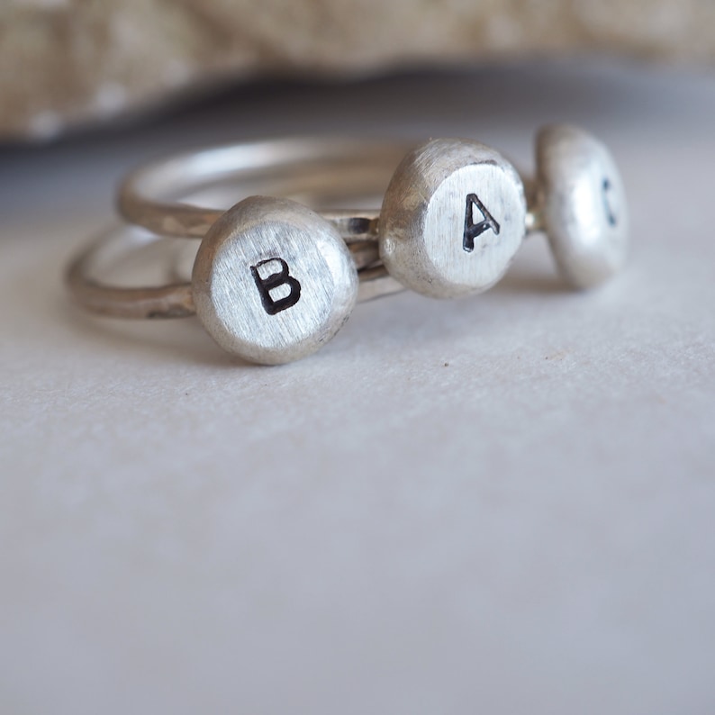 May include: Three silver rings with the letters A, B, and C engraved on them.