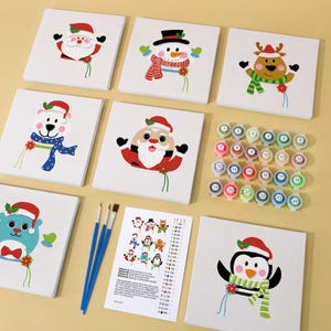 May include: A paint-by-number kit featuring Christmas-themed characters on square canvases. The kit includes Santa Claus, a snowman, a reindeer, a polar bear, a penguin, and an elf. Also included are paint pots and paintbrushes.